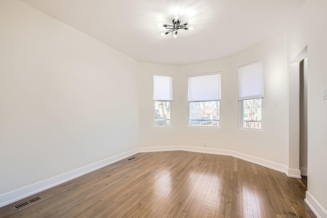 spare room featuring hardwood / wood-style floors, baseboards, and visible vents