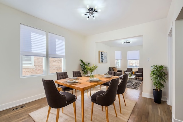 dining area with visible vents, baseboards, and wood finished floors