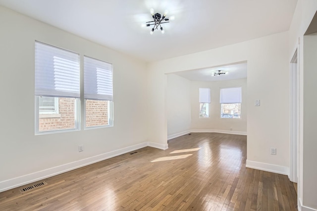 spare room with visible vents, baseboards, and hardwood / wood-style floors