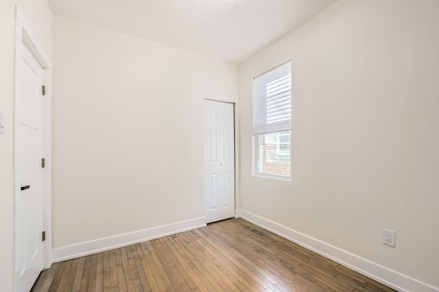 unfurnished room featuring visible vents, baseboards, and hardwood / wood-style floors