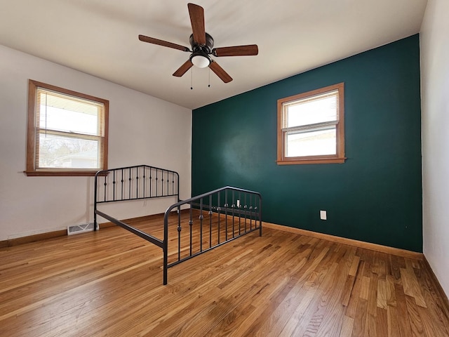 bedroom featuring multiple windows, wood finished floors, and baseboards