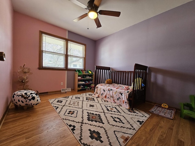 bedroom featuring ceiling fan, visible vents, baseboards, and wood finished floors