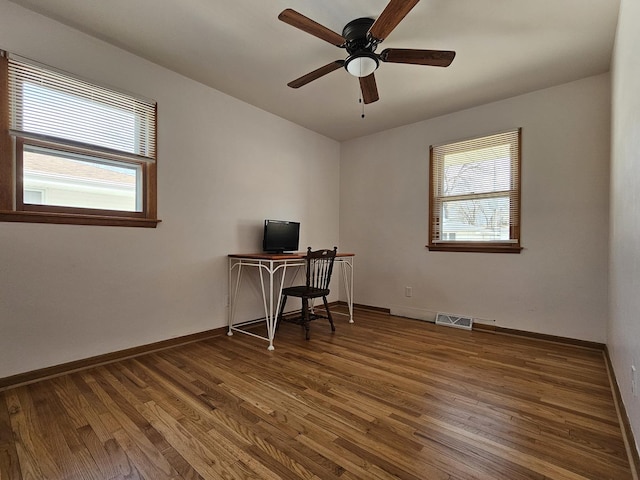 home office with ceiling fan, visible vents, baseboards, and wood finished floors