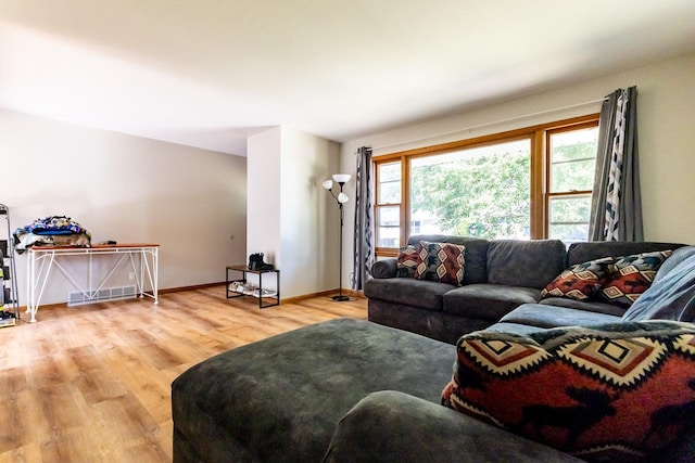 living room featuring baseboards, plenty of natural light, visible vents, and wood finished floors