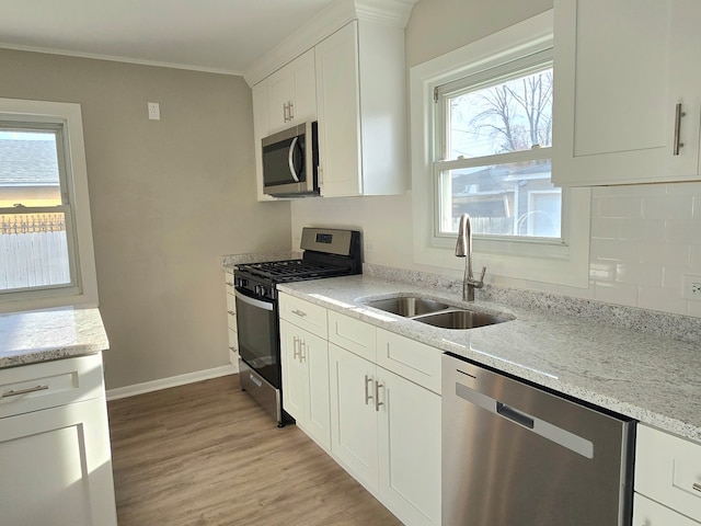 kitchen featuring a sink, light wood-style flooring, light stone countertops, and stainless steel appliances