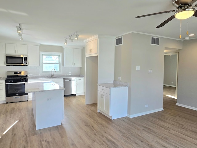 kitchen featuring visible vents, stainless steel appliances, crown molding, and a sink