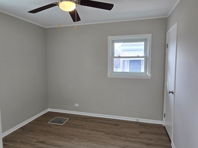 empty room featuring a ceiling fan, baseboards, visible vents, dark wood-style flooring, and ornamental molding