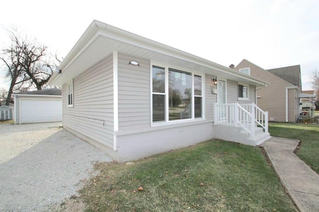 bungalow-style home featuring an outbuilding, a garage, and a front lawn