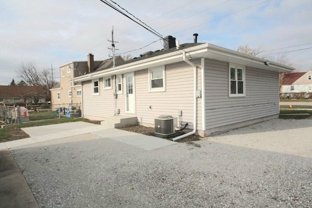 rear view of house with cooling unit and a chimney