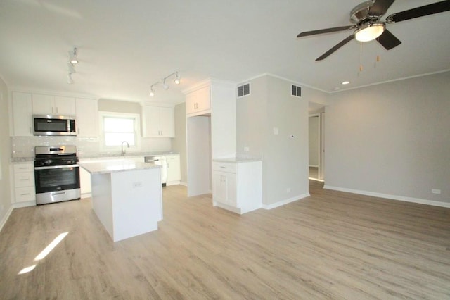 kitchen featuring visible vents, open floor plan, appliances with stainless steel finishes, white cabinets, and a sink