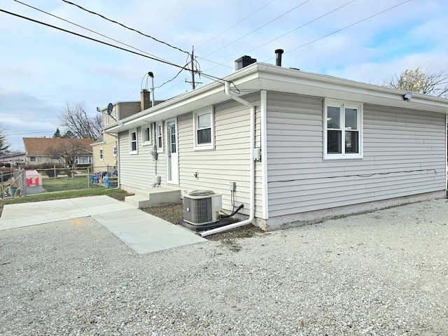 exterior space featuring central air condition unit, a chimney, and fence