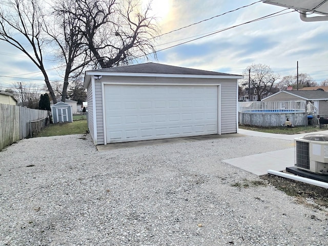 detached garage featuring fence and central AC