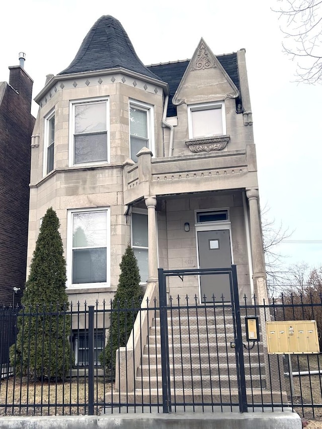 victorian-style house featuring a fenced front yard and stone siding