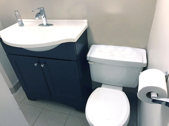 half bathroom with tile patterned flooring, toilet, and vanity