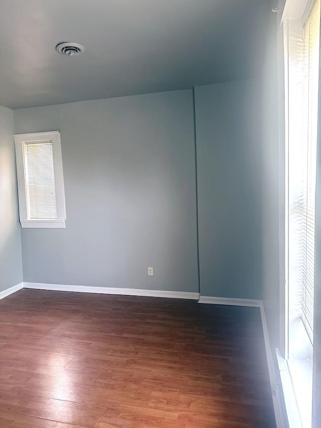 spare room featuring wood finished floors, visible vents, and baseboards