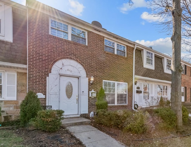 multi unit property with brick siding and a shingled roof