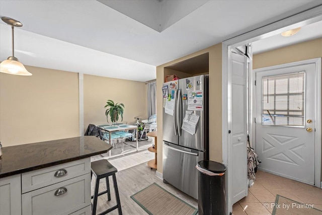 kitchen with hanging light fixtures, a breakfast bar area, light wood-type flooring, and freestanding refrigerator