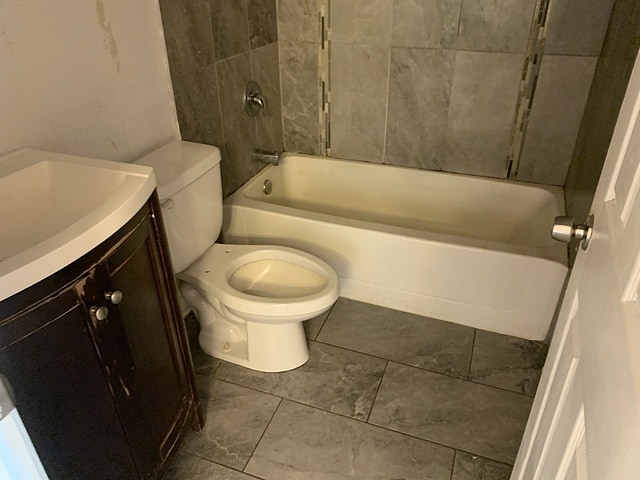 bathroom featuring toilet, vanity, and bathtub / shower combination