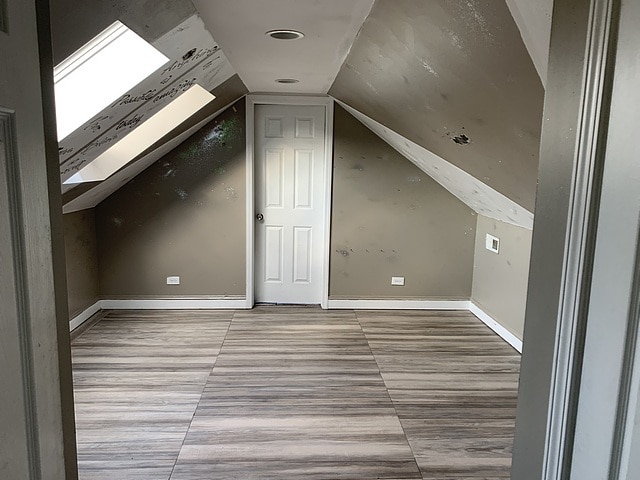 additional living space with lofted ceiling with skylight and baseboards