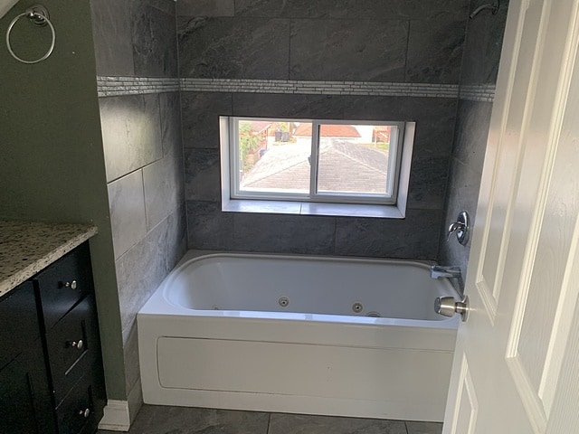 bathroom featuring a tub with jets, vanity, and tile patterned flooring