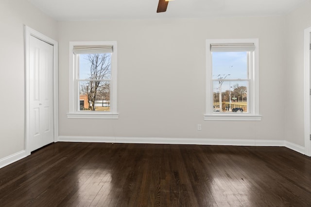 spare room with dark wood finished floors, baseboards, and a ceiling fan