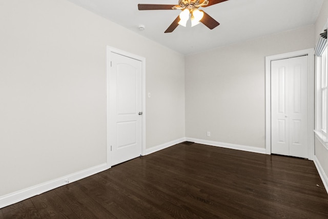 empty room with baseboards, dark wood finished floors, and a ceiling fan