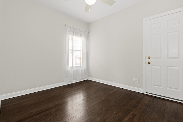 unfurnished room with baseboards, a ceiling fan, and dark wood-style flooring