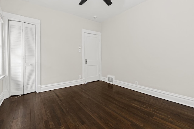 unfurnished bedroom featuring a closet, visible vents, dark wood-type flooring, and baseboards