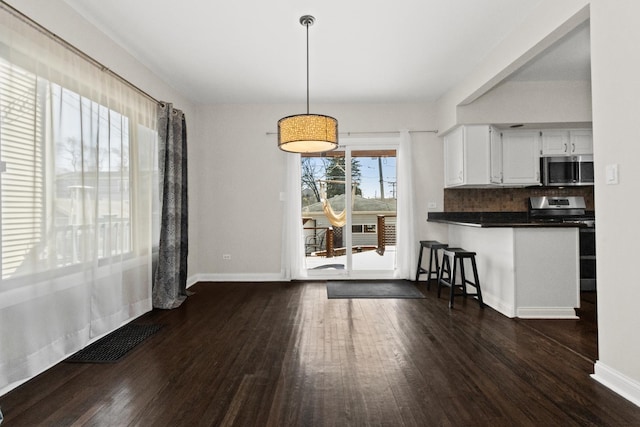 unfurnished dining area featuring dark wood finished floors, visible vents, and baseboards