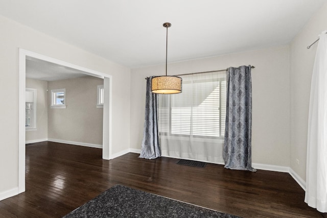 unfurnished dining area with wood finished floors, visible vents, and baseboards