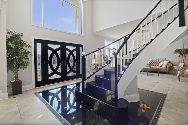 tiled entrance foyer with stairway, baseboards, and a towering ceiling