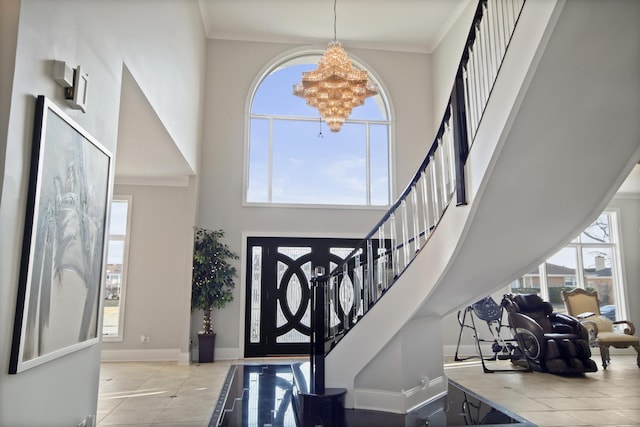 tiled entrance foyer featuring plenty of natural light, a high ceiling, an inviting chandelier, and crown molding