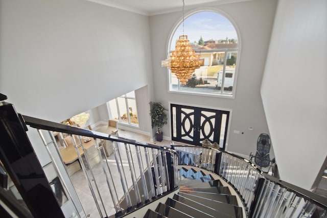 stairway with crown molding, baseboards, a towering ceiling, and a chandelier