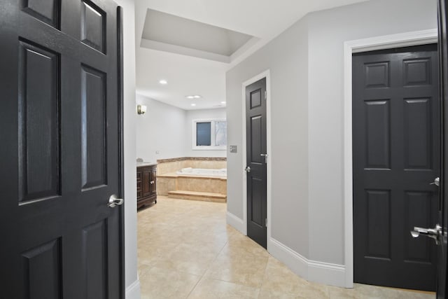 bathroom featuring tile patterned floors, a bath, and baseboards