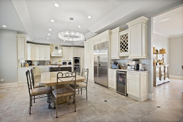 kitchen featuring beverage cooler, premium range hood, stainless steel appliances, decorative backsplash, and light countertops