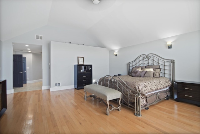 bedroom featuring visible vents, light wood-type flooring, baseboards, and vaulted ceiling