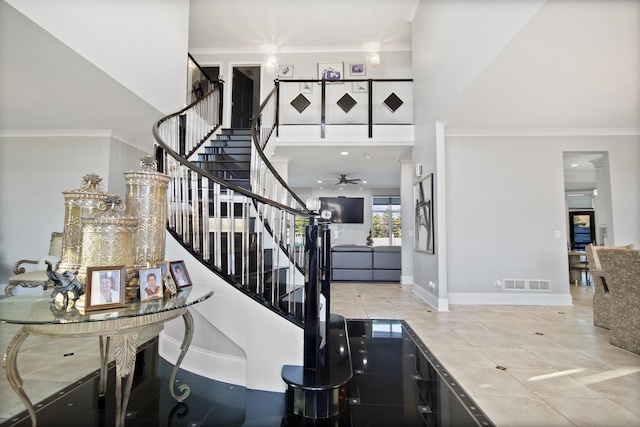 stairs featuring visible vents, a ceiling fan, a high ceiling, and crown molding