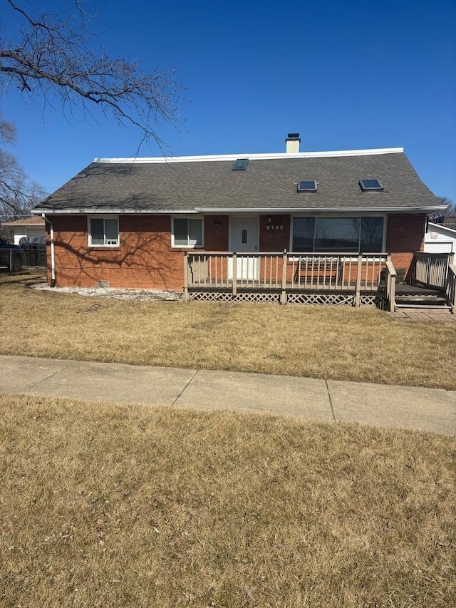 ranch-style house with a wooden deck, a shingled roof, and a front lawn