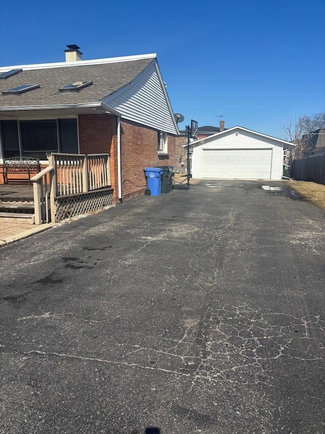 view of property exterior with a garage, an outbuilding, brick siding, and a chimney