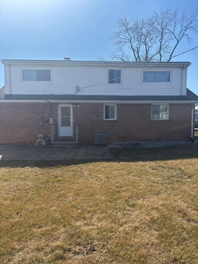 rear view of house with brick siding, entry steps, cooling unit, a yard, and a patio