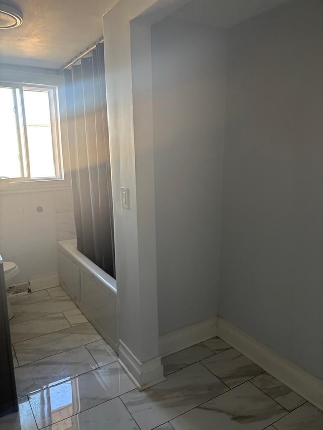 full bathroom with toilet, baseboards, marble finish floor, and shower / tub combo with curtain