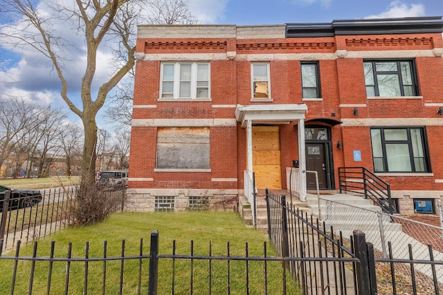 view of front of property featuring a fenced front yard, brick siding, and a front lawn