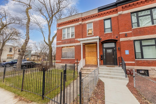 multi unit property featuring a fenced front yard and brick siding