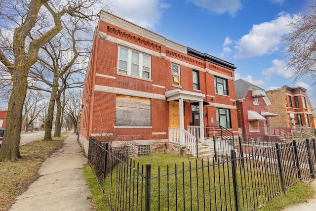 townhome / multi-family property featuring a front yard, a residential view, brick siding, and a fenced front yard