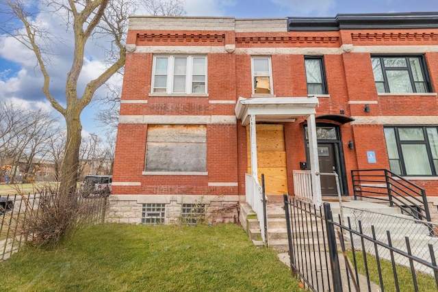 townhome / multi-family property featuring a front lawn, fence, and brick siding