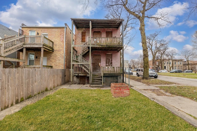 back of property with stairs, a yard, fence, and brick siding