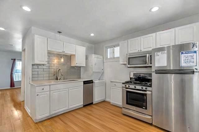 kitchen featuring a sink, appliances with stainless steel finishes, white cabinets, and light countertops