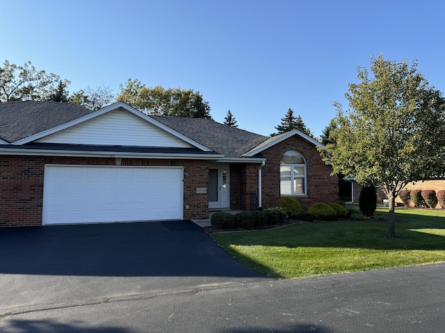 ranch-style home featuring aphalt driveway, an attached garage, brick siding, and a front lawn