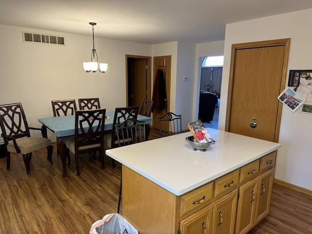 kitchen with dark wood finished floors, light countertops, hanging light fixtures, and visible vents