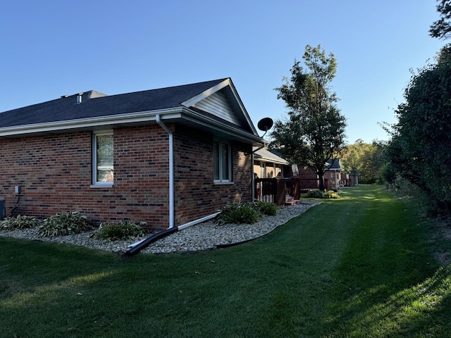 view of side of home featuring a lawn and brick siding